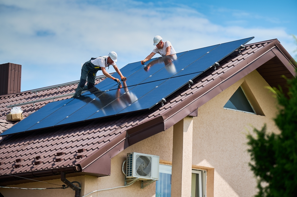 2 techniciens qui installent des panneaux solaires sur le toit d'une maison