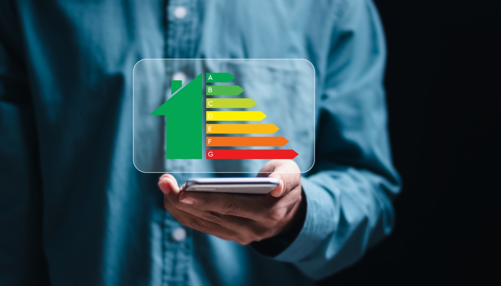 Une personne utilise un smartphone avec écran virtuel de la cote d'efficacité énergétique pour vérifier le taux